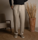 Person wearing beige pants standing in a room with a chair and vase of sticks.
